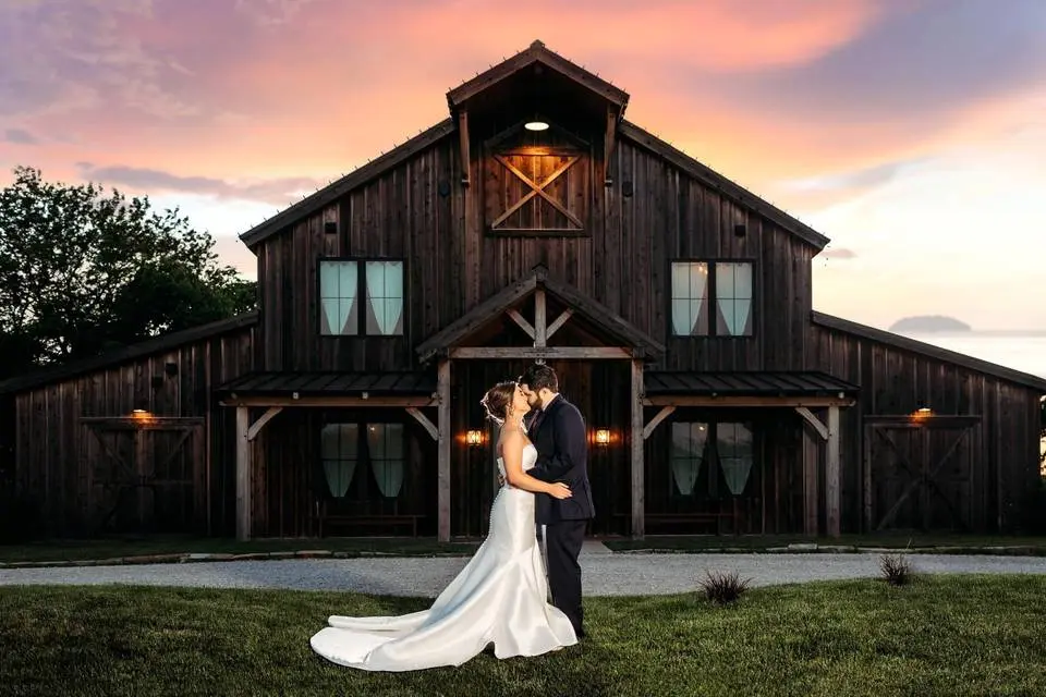 gorgeous couple Couple embracing in front of The Pearl at Crawford Farm, a rustic wedding venue, during sunset, showcasing charming wooden architecture and romantic atmosphere.