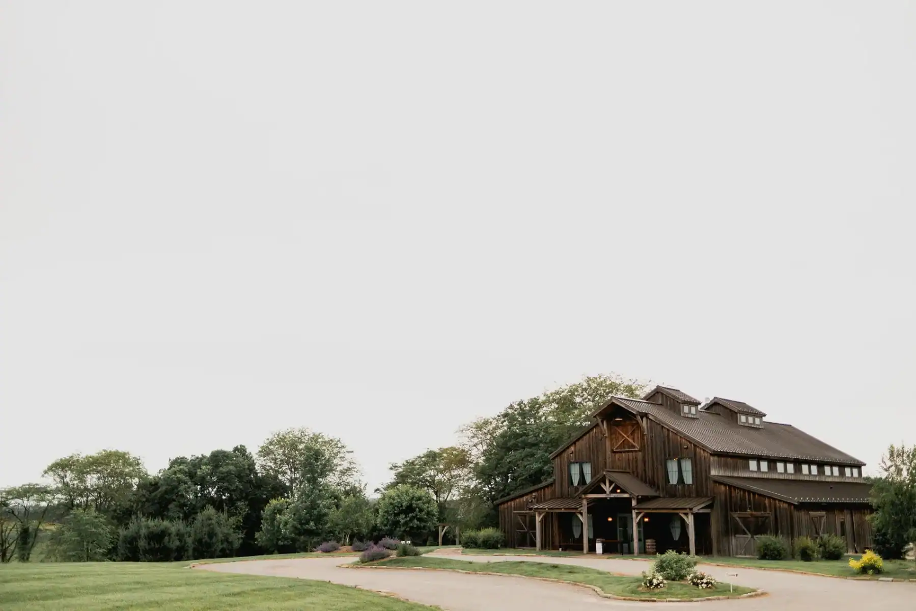 Modern barn venue at The Pearl at Crawford Farm, surrounded by lush greenery and a winding driveway, ideal for weddings near Manhattan, KS.